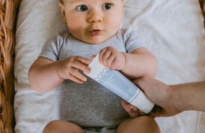 Baby auf Wickeltisch mit med Wundcreme für wunden Babypo in der Hand