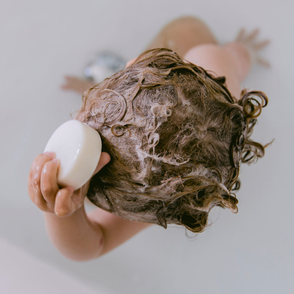 Kind seift sich die Haare mit Shampoostückchen festes Shampoo von das boep ein