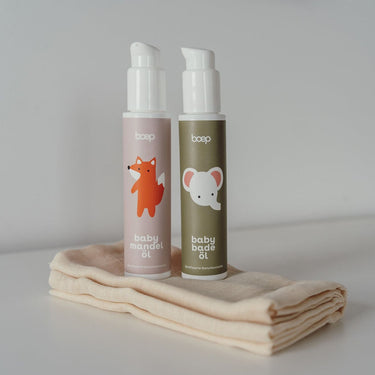 Geschenk zur Geburt für die Erstausstattung mit Naturkosmetik Babymandelöl und Babybadeöl von das boep stehen auf einem Mulltuch