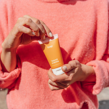 Frau hält Handcreme von das boep als Pflegecreme bei trockener Haut in der Hand