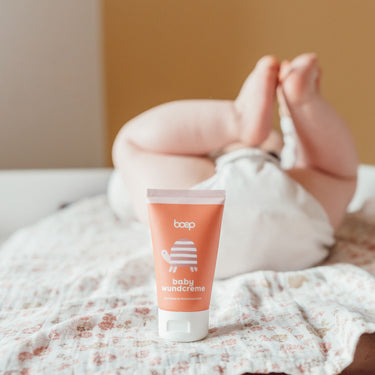 Naturkosmetik Babywundcreme von das boep für wunden Babypo steht auf einem Wickeltisch und im Hintergrund liegt ein Baby.