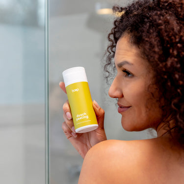 Frau hält das Naturkosmetik Duschpeeling von das boep zur sanften Entfernung von Hautschuppen in der Hand