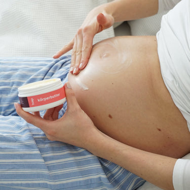 Eine schwangere Frau cremt ihren Babybauch mit der Körperbutter von das boep ein