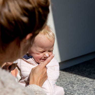 Kind wird mit med Sonnenbalsam für trockene Haut und Neurodermitis von das boep eingecremt