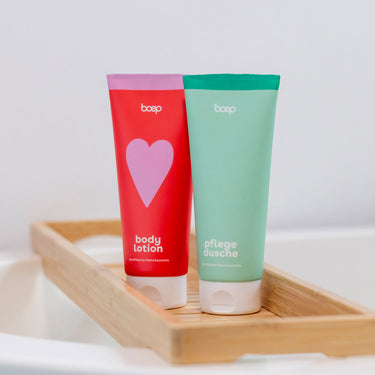 Wohlfuehl Bundle von das boep bestehend aus einem Duschzeug und einer Bodylotion als Geschenk für Schwangere stehen auf einem Holztablett
