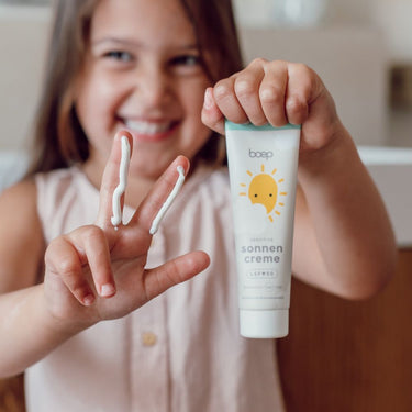 Mädchen zeigt mineralische Sonnencreme Sensitiv LSF 50 von das boep